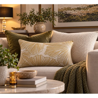 Gold and white leaf pattern cushion on cream sofa with olive knit throw