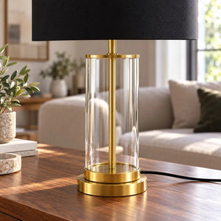 Gold plated glass lamp close up of clear cylinder and two tier base on timber table