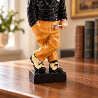 Golfer statue close up of crossed legs two tone shoes and black base on wooden table