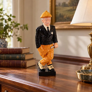 Golfer statue on wooden sideboard beside brass table lamp and leather books