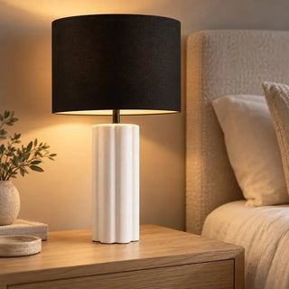 Horizon ceramic lamp glowing on light oak nightstand beside boucle headboard