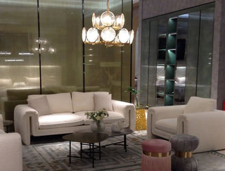 Modern living room with white sofa set, gold chandelier, and round coffee tables