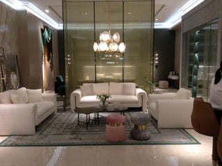 Modern living room with white sofas, contemporary lighting, and velvet ottomans