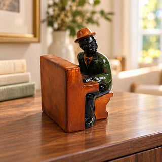 Jazz pianist statue on timber sideboard beside stacked books and white vase