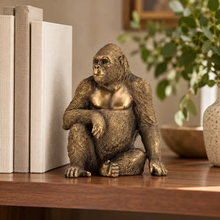 King kong gorilla ornament on walnut shelf beside linen books and speckled vase