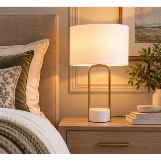 Luna arc ceramic lamp lit on oak bedside table beside linen headboard