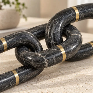 Marble chain sculpture close up of interlocking dark grey links and brass bands