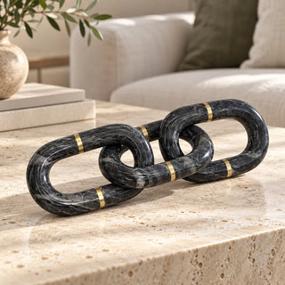 Marble chain sculpture dark grey with brass bands on travertine coffee table beside sofa