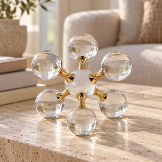 Molecular crystal ball ornament on travertine coffee table beside cream sofa