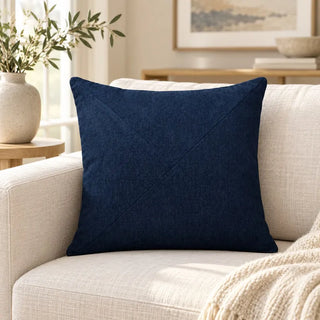 Navy textured cushion on cream sofa with knit throw and olive branches