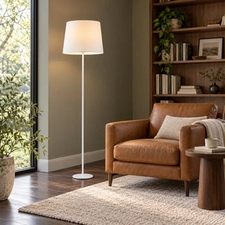 Newport white floor lamp beside tan leather armchair and walnut bookshelf