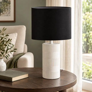 Norman ceramic lamp on round timber side table beside cream armchair and window