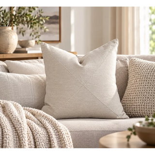 Oatmeal textured cushion on cream sofa beside chunky knit cushion