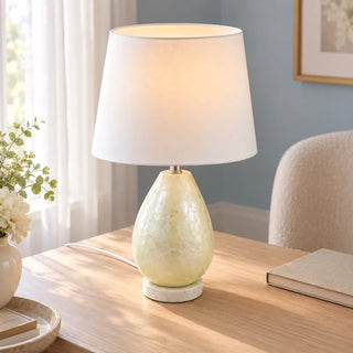 Pearl capiz table lamp on oak desk beside boucle chair and blue grey wall