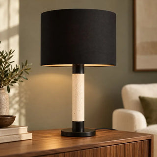 Raffle lamp with travertine stone and black shade on walnut sideboard beside armchair