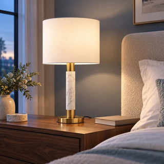 Raffle table lamp lit on walnut bedside cabinet beside boucle headboard