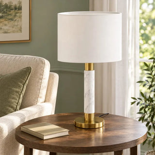 Raffle table lamp on round timber side table beside cream armchair in sage green room