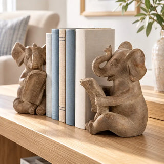 Reading elephant bookend set on light oak console with blue and cream books near armchair