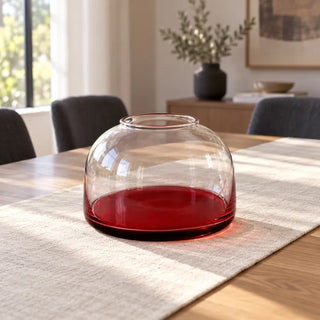 Red bottom glass vase on oak dining table with linen runner and charcoal chairs