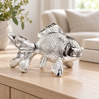 Silver metallic fish figurine on light oak sideboard beside cream sofa