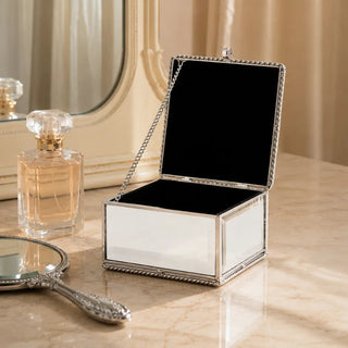 Silver mirror jewellery box open beside a perfume bottle and hand mirror