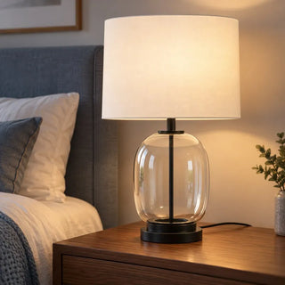 Soho glass lamp lit on walnut bedside table beside blue grey headboard