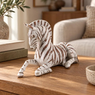 Whitewashed zebra figurine on timber coffee table beside cream sofa and stacked books