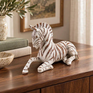 Whitewashed zebra figurine on walnut sideboard beside framed landscape print